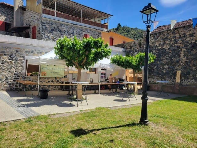 Place du village et bâtisses en pierre, avec les monts en arrière-plan